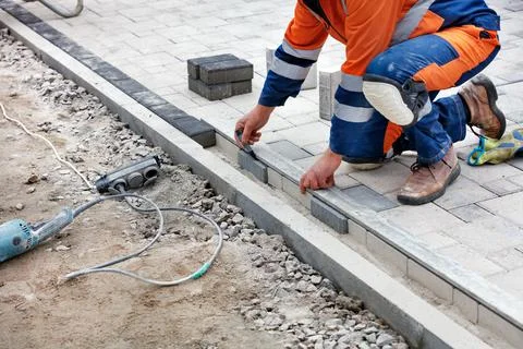 The bricklayer uses a black marker and an aluminum level to measure out a por Stock Photos