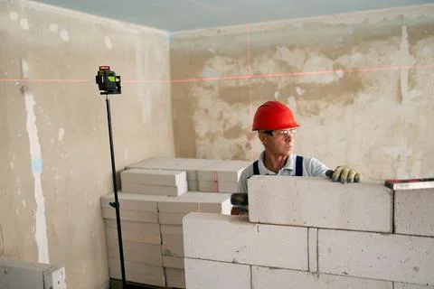 Bricklayer using rubber mallet hammer to tap and level concrete blocks wall Stock Photos