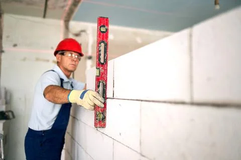 Bricklayer using spirit bubble and laser level to precise check concrete blocks Stock Photos