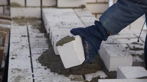 A bricklayer in winter on a construction site aligns bricks laid in cement. 스톡 사진