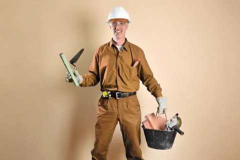 Bricklayer in work clothes holding tools and building materials isolated Stock Photos