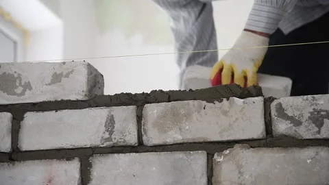 Bricklayer worker installing brick masonry on exterior wall Vídeos de archivo 165561799