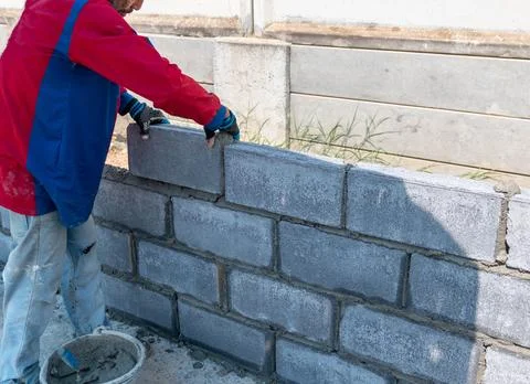 Bricklayer worker installing brick masonry on exterior wall. Stock Photos