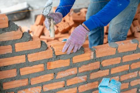 Bricklayer worker installing brick masonry on interior wall with trowel put.. Foto stock