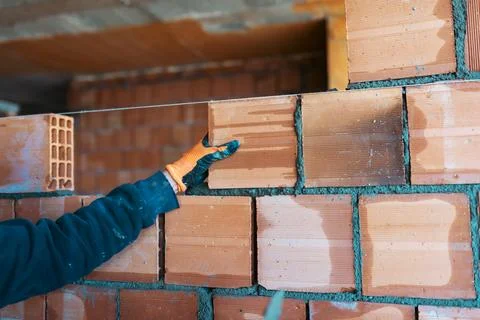 Bricklayer worker installing bricks on construction site Stock Photos