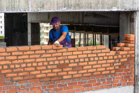 Bricklayer worker laying brick on mortar, building partition wall in building Stock Photos