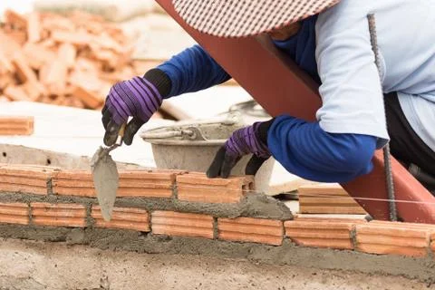 Bricklayer working in construction site of a brick wall Stock Photos