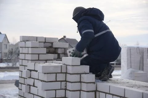 Bricklayer working on a construction site, laying concrete blocks. Stock Photos
