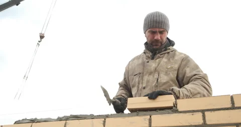 Bricklayer works at construction site, taps masonry with trowel, builds wall Stock Footage 144164218