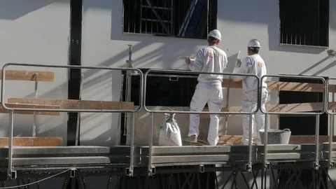 Bricklayers mounted on a scaffold work on the facade of a building Stock Footage 102759278