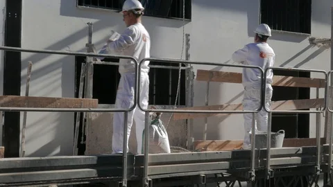 Bricklayers mounted on a scaffold work on the facade of a building Stock Footage 102821591