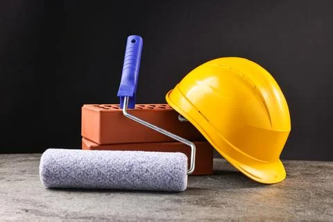 Bricks, hardhat and paint roller on grey table Stock Photos