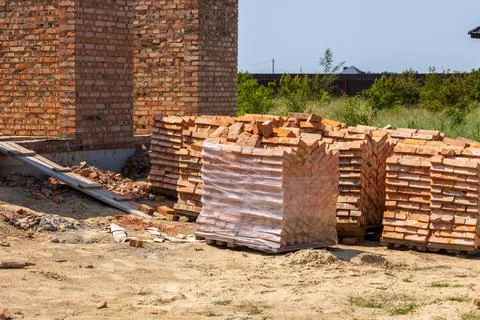 Bricks neatly stacked on pallets at a construction site, indicating ongoing.. 写真素材