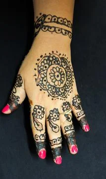 Bridal mehendi pattern with elegant black henna artwork on fingers and palm Stock Photos