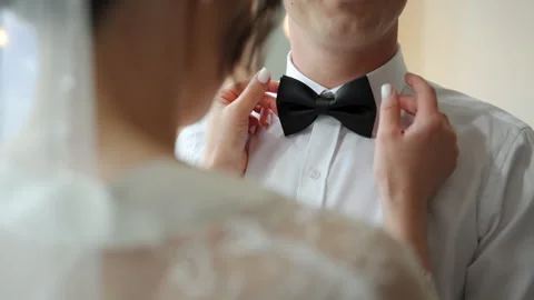 Bride adjusting Groom bow tie while getting ready for the wedding, capturing an Stock Footage 324242342