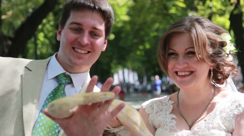 The bride and groom are playing with a live snake on the street Video stock 58973802