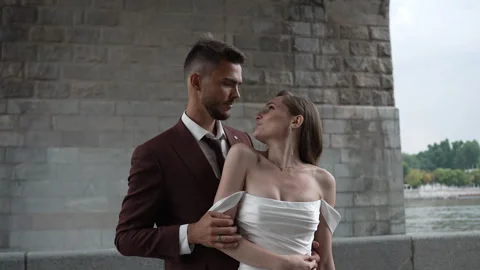 A bride and groom are posing for a picture in front of a bridge Vidéo 267879324