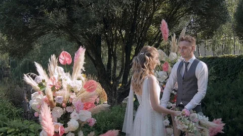 The bride and groom on the background of the wedding arch and look at each other Stock Footage 127835976