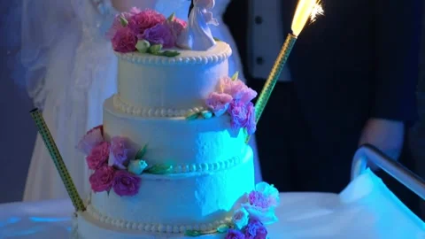 Bride and groom cutting decorated wedding cake indoors at nighttime Video stock 342135199