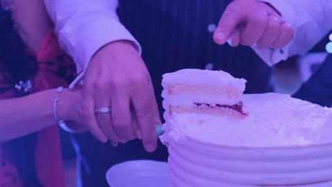 Bride and groom cutting multi-tiered wedding cake indoors at nighttime Video stock 342018299