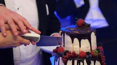Bride and groom cutting wedding cake indoors at nighttime reception Video stock 342028685