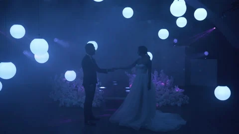 The bride and groom dance the first dance on stage, around them laser projection Stock Footage 150380935