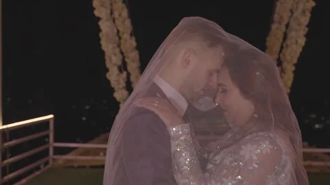 Bride and Groom Embracing Under Falling Veil at Night Stock Footage 314622909