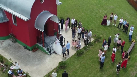 The bride and groom enter the red Orthodox church Stock Footage 211795980