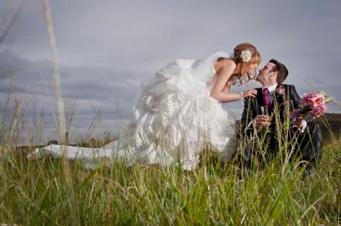 Bride and Groom in a field sharing wine. Stock Photos