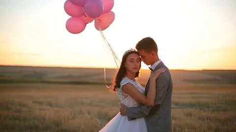 Bride and groom in a field at sunset with balloon Stock Footage 80664402