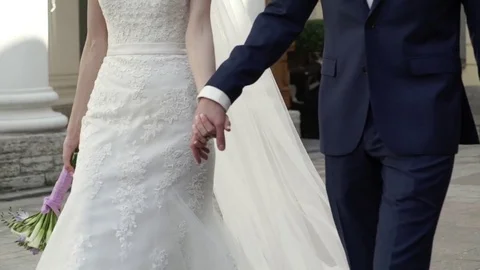Bride and groom holding hands and walking in a city Stock Footage 80791552