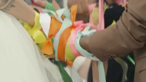 Bride and groom holding hands wrapped in colorful ribbons, symbolizing unity Video stock 316802402