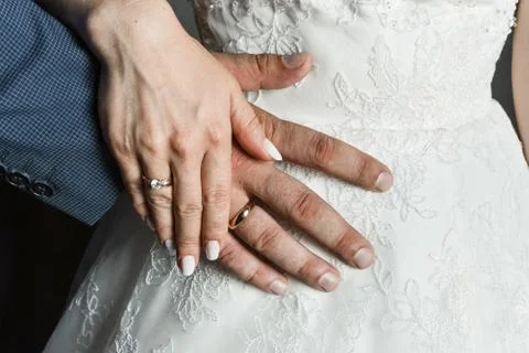Bride and groom holding hands with golden wedding rings. White lace dress of the Stock Photos