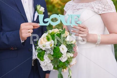 Bride and groom holding wooden word love Stock Photos