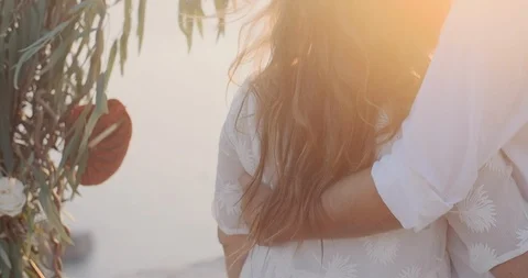 Bride and groom hug at the wedding arch and watch the sunset Stock Footage 123783232