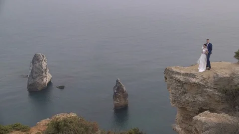 Bride and groom posing on the edge of the cliff background of the sea Video stock 94214599