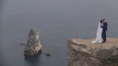 Bride and groom posing on the edge of the cliff background of the sea Stock Footage 94215619