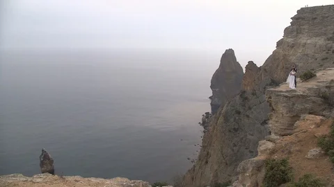 Bride and groom posing on the edge of the cliff background of the sea Stock Footage 94215657