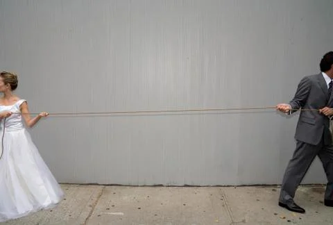 A bride and groom pulling a rope in different directions Stock Photos