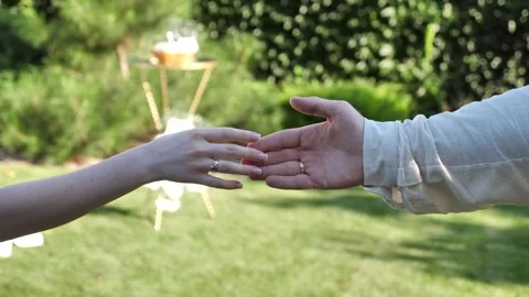 Bride and groom reaching for each other's hands at an outdoor wedding ceremony. Stock Footage 343686381