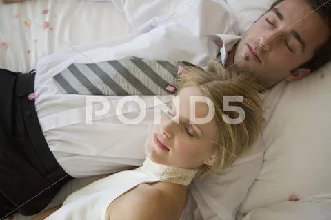 A bride and a groom resting on a bed together Stock Photos
