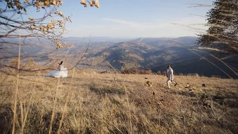 Bride and groom run to each other in the autumn mountains. wide low view from Stock Footage 121320593