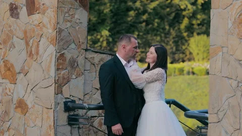 Bride and Groom Sharing Tender Moment by Stone Wall, A bride and groom stand Stock Footage 290778313