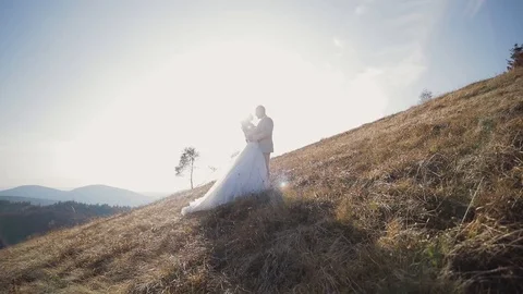 Bride and groom stand in front each other in the autumn mountains. wide view. a Stock Footage 121320368