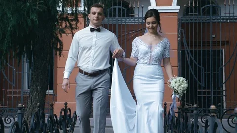 Bride and groom strolling on the background of urban architecture Stock Footage 107657729