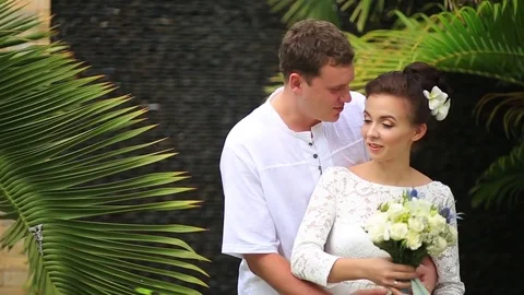The bride and groom surrounded by palm trees looking into the distance Stock Footage 76180185