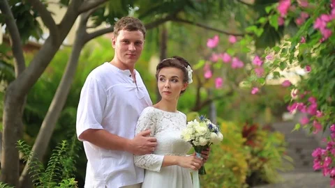 The bride and groom surrounded by palm trees looking into the distance Stock Footage 76180253