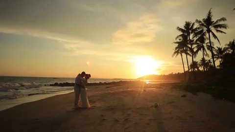The bride and groom surrounded by palm trees looking into the distance Stock Footage 76180737
