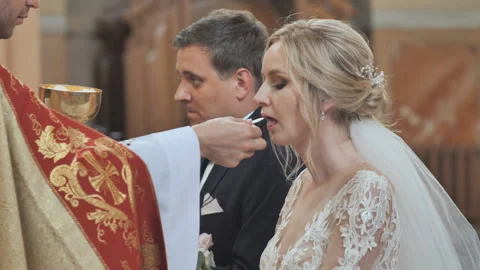 The bride and groom take communion in the Catholic Church. Stock Footage 119330458