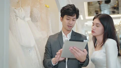 Bride and groom using tablet for choosing a wedding clothing in the wedding shop Stock Footage 231743850